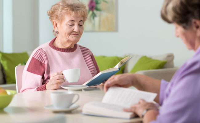 two nice elderly women reading books in living room